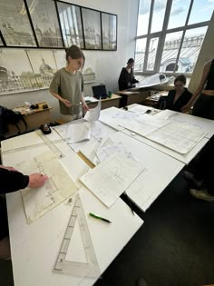 several people sitting around a table with drawings and pencils on it in an office