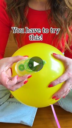 a woman sitting on the floor holding a yellow ball with text that reads, you have to try this