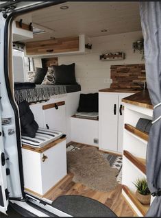 the interior of a camper van with wood flooring and white cabinets in it