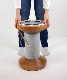 a woman standing over a wooden table with a spool of thread on top of it