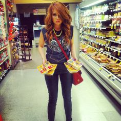 a woman standing in front of a store filled with food