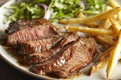 steak sliced up on a cutting board with garlic next to it