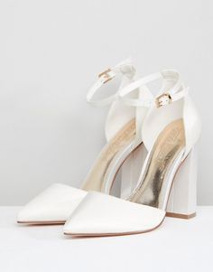 a pair of white high heeled shoes on top of a white surface with one shoe in the middle