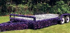 a lawn mower covered in purple flowers sitting on top of a lush green field