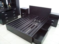 a black bed frame with drawers and night stands next to it in a room that has white tile flooring