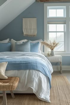 a bed sitting under a window in a bedroom next to a wooden bench and chair