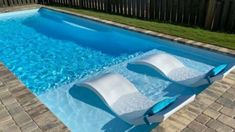 an in ground swimming pool with two lounge chairs on the bottom and water running down it