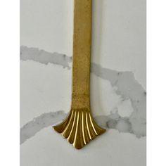 a gold colored metal object on a white marble counter top, with the bottom part of it's tail shaped like a fish