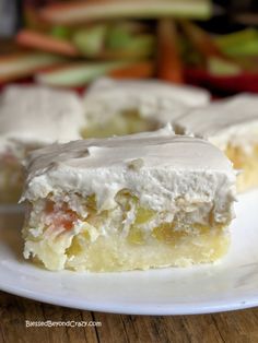 a piece of cake on a plate with icing and apples in the back ground