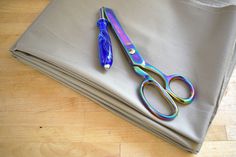 a pair of scissors sitting on top of a gray cloth next to a folded sheet