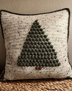 a crocheted christmas tree pillow on a wicker chair