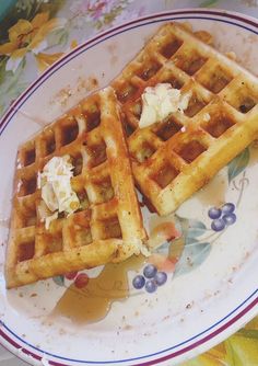 two waffles sitting on top of a white plate with blueberries and whipped cream