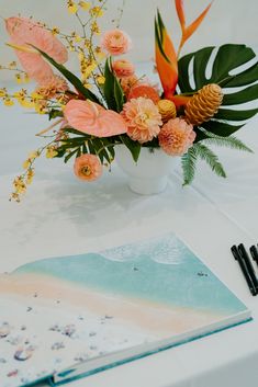 a vase filled with flowers on top of a table next to a notebook and pen