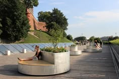 a woman is sitting on a bench in the middle of a walkway with plants growing out of it