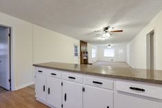 an empty kitchen with white cabinets and granite counter tops is seen in this image from the doorway