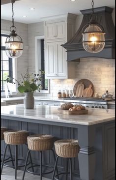 a kitchen island with stools and lights hanging from it's ceiling over the counter