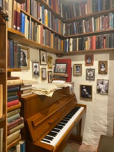 there is a piano in the room with many books on the shelves and pictures around it