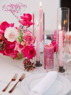 the table is set with pink flowers, candles and silverware for an elegant dinner