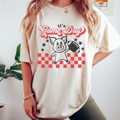 New product- Vintage Pig Game Day Shirt! Get ready to show off your pride with our Vintage Pig Shirt, a must-have for fans! This unique design combines a vintage style with the fierce spirit, creating a shirt that stands out from the crowd. Each shirt is meticulously printed by me using high-quality materials on a Comfort Colors shirt, known for its exceptional comfort and durability. Whether you're cheering on your team at the stadium or simply want to showcase your school spirit in your everyday attire, this shirt is the perfect choice. Available in sizes S to 3X, we've got you covered regardless of your preferred fit. The shirt features a classic crew neck and short sleeves, making it suitable for year-round wear. The flattering silhouette ensures a comfortable and stylish fit for both Screen Print Shirt For Game Day Fan Apparel, Sports Fan Shirt With Graphic Print For Game Day, Sports Fan Cotton Shirt With Graphic Print, Graphic Tee Shirt With Heat Transfer Vinyl For Fans, Game Day Fan Apparel Shirt With Screen Print, Fan Apparel Shirt With Screen Print For Game Day, Game Day Crew Neck Shirt With Sublimation Print, Screen Print Shirt For Game Day, Team Spirit Graphic Print Shirt For Game Day