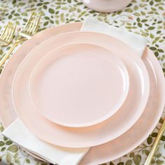 the table is set with pink plates and gold cutlery, along with white napkins