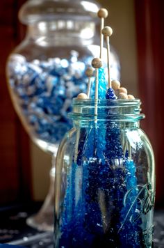 a jar filled with blue and white candies on top of a table next to a vase