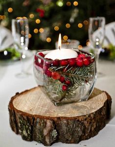 a glass bowl filled with red berries sitting on top of a wooden slice