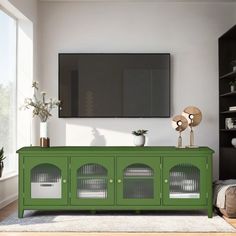 a living room with a green cabinet and white rugs on the floor next to a large flat screen tv