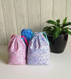 three bags sitting next to a potted plant on top of a white countertop