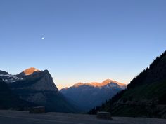 the sun is setting over some mountains and trees