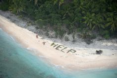 an aerial view of people walking on the beach with words help written in sand and palm trees