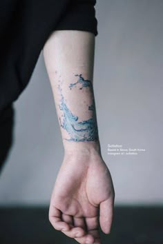 a person with a blue wave tattoo on their left arm and wrist is holding the other hand