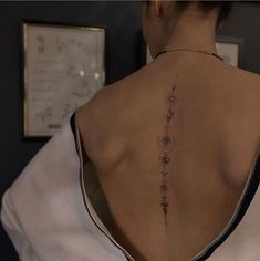 the back of a woman's neck with tattoos on her upper and lower back