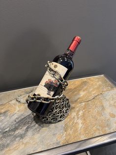 a bottle of wine sitting on top of a metal stand with a chain around it