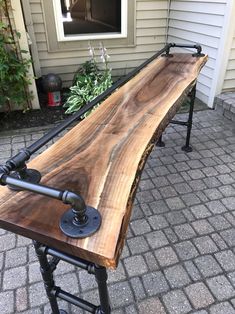 a bench made out of wood and pipes on the side of a house with a potted plant