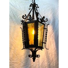 an old fashioned hanging lantern with a candle lit up in the dark on a white background