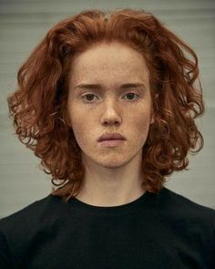 a woman with freckles on her face is looking at the camera while wearing a black t - shirt