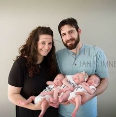 a man and woman holding two babies in their arms