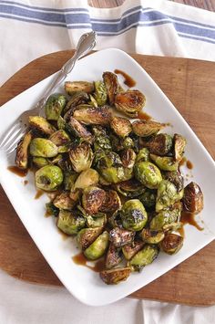 brussel sprouts on a white plate with a fork and sauce drizzled over them