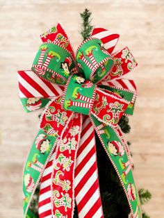 a green and red bow on top of a christmas tree with candy canes around it