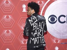 a man with an afro standing in front of a red wall