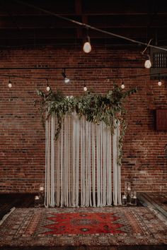 an area rug with candles and greenery on it in front of a brick wall