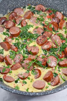 a pizza with sausage, spinach and cheese in a pan