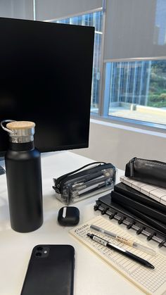 an office desk with a computer monitor, cell phone and other items sitting on it