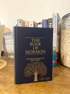 the book of mormon is sitting on a table next to some books and other items