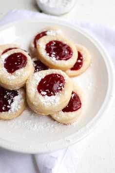 small pastries with powdered sugar and jelly on a white plate, ready to be eaten