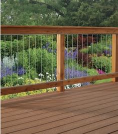 a wooden deck with metal railing and flowers in the background