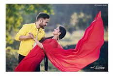 a man and woman are dancing together in the grass with red cloths on their shoulders