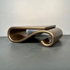 an unusual coffee table made out of metal and wood, with a curved design on the top