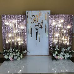 a table with flowers and candles on it in front of a door decorated with lights