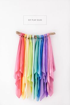 a rainbow colored scarf hanging on a white wall with the words diy play silks above it